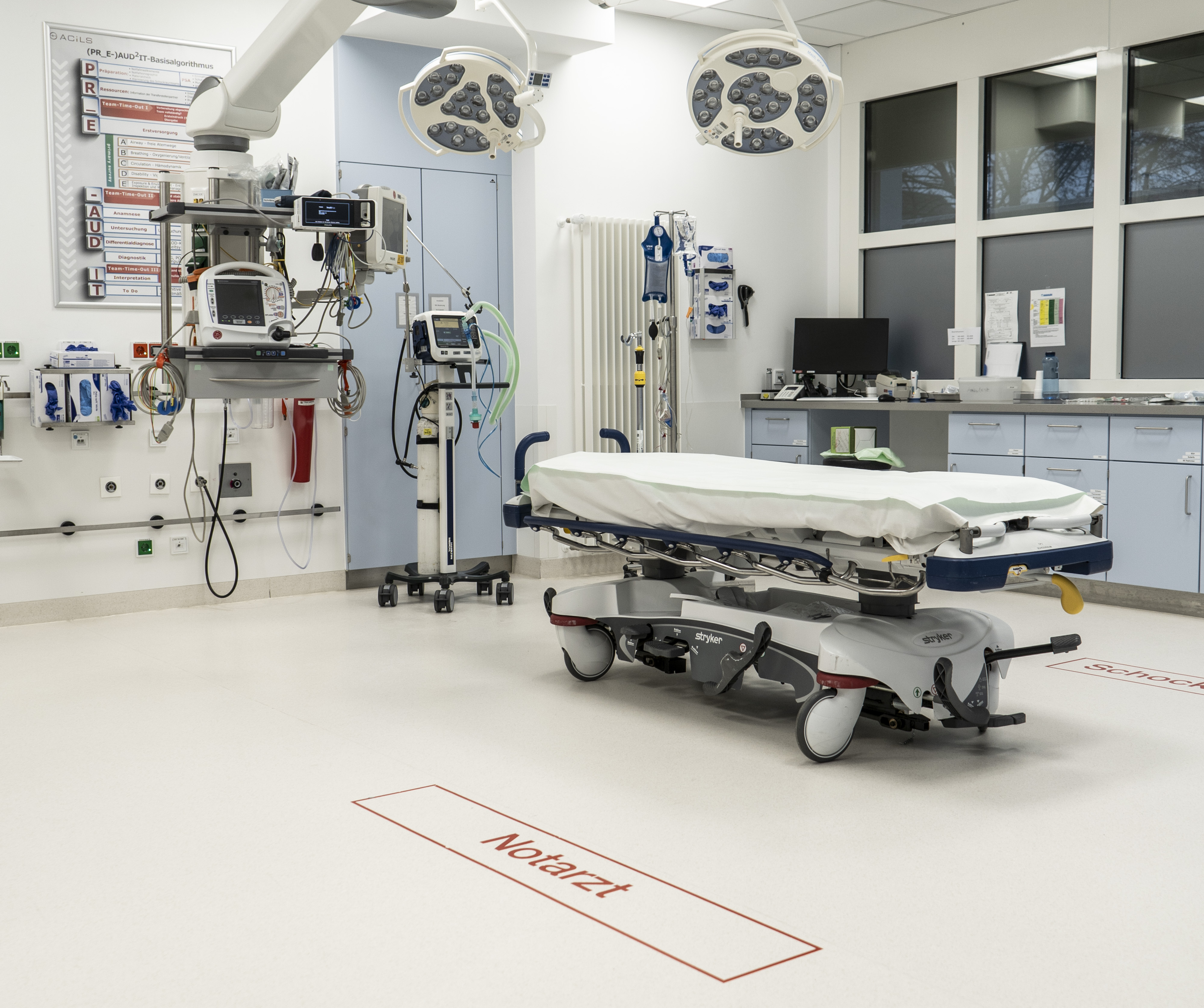 Moderner Notarzt-Behandlungsraum mit Untersuchungsliege und medizinischen Geräten.